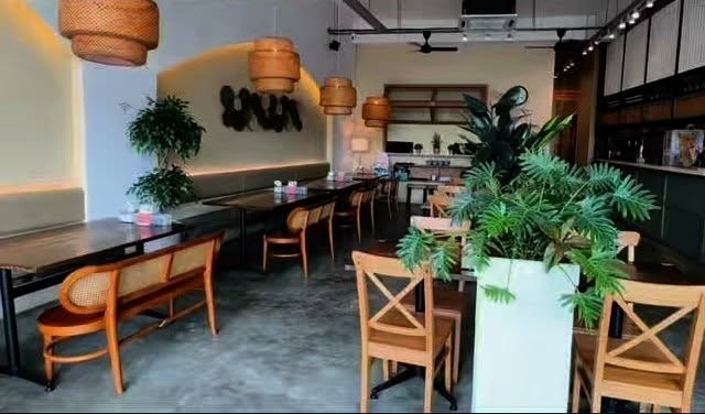 Inside Thamada Village Larkin: wooden chairs, rattan pendant lamps, plants